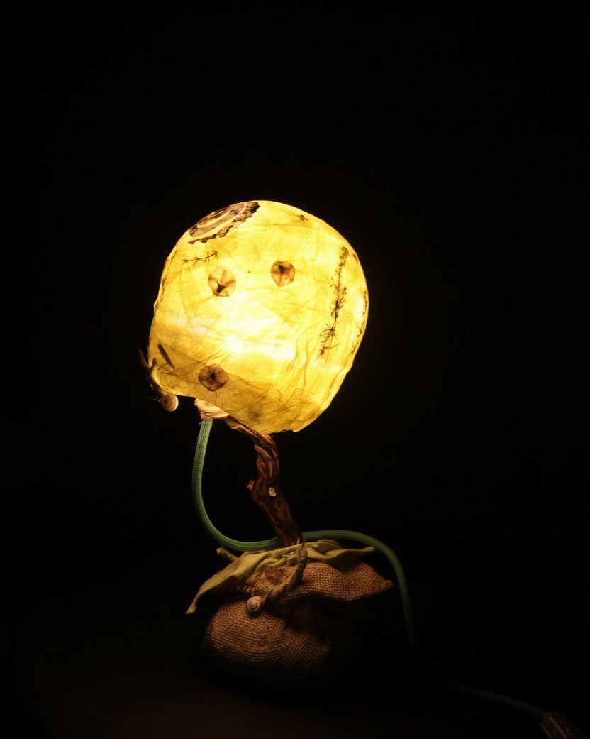 Pequeña lámpara con forma de flor sobre una base de piedras de río.